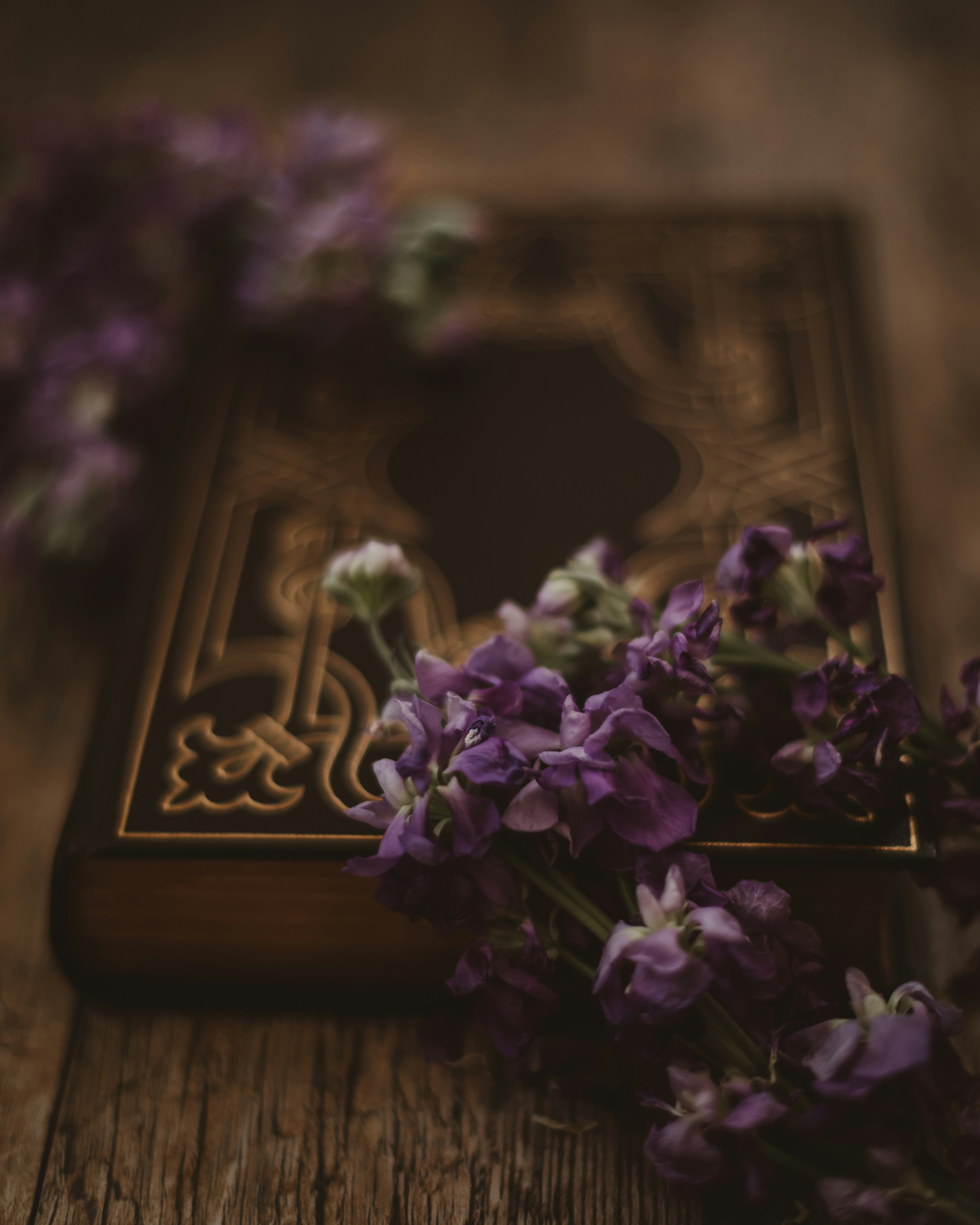 selective focus photography of purple flowers on closed book